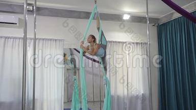 年轻女子在室内的吊床上练习飞行瑜伽。